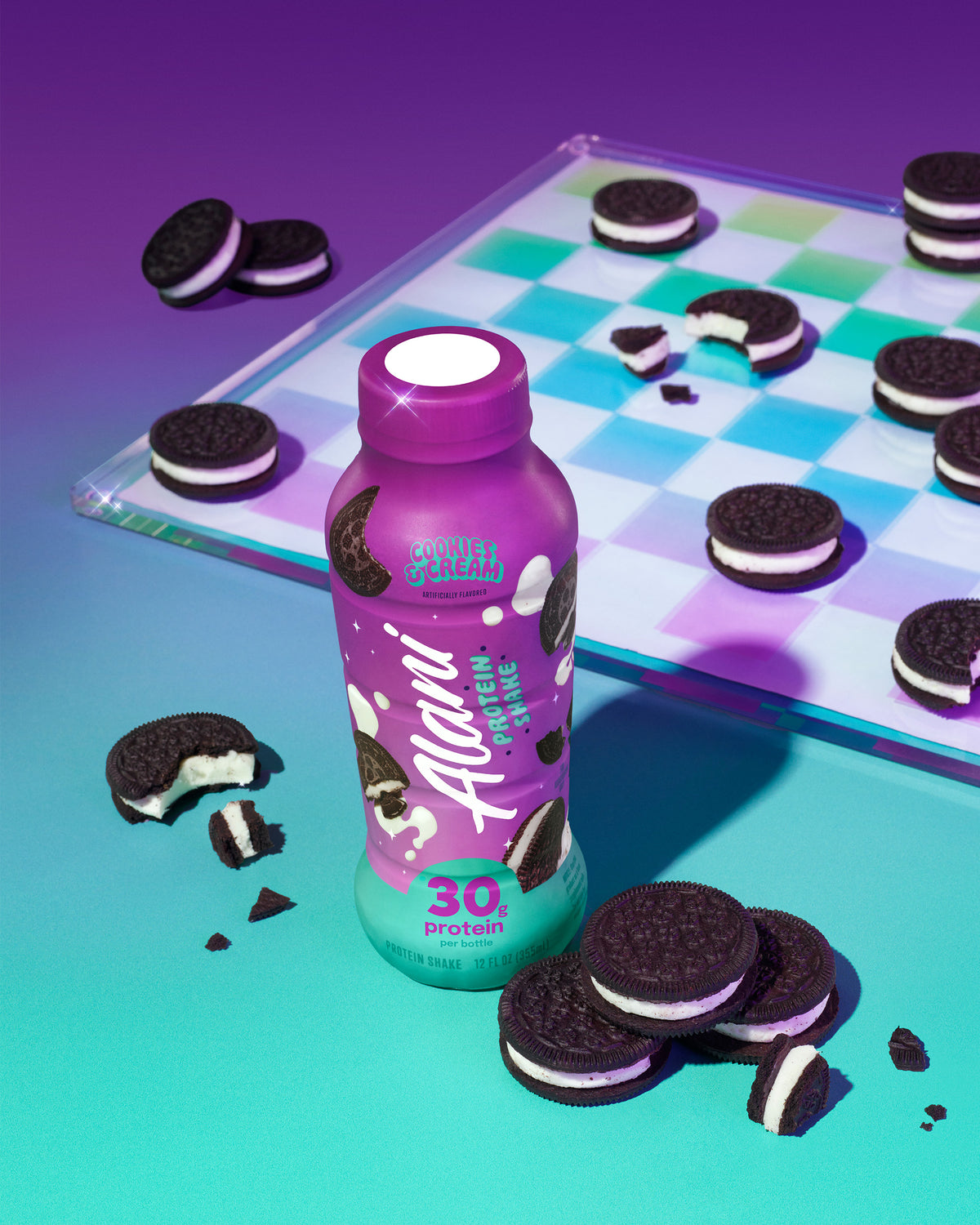 An overhead shot of an Alani Nu Cookies &amp; Cream Protein Shake surrounded by classic chocolate sandwich cookies with a rainbow checkers board in the background.