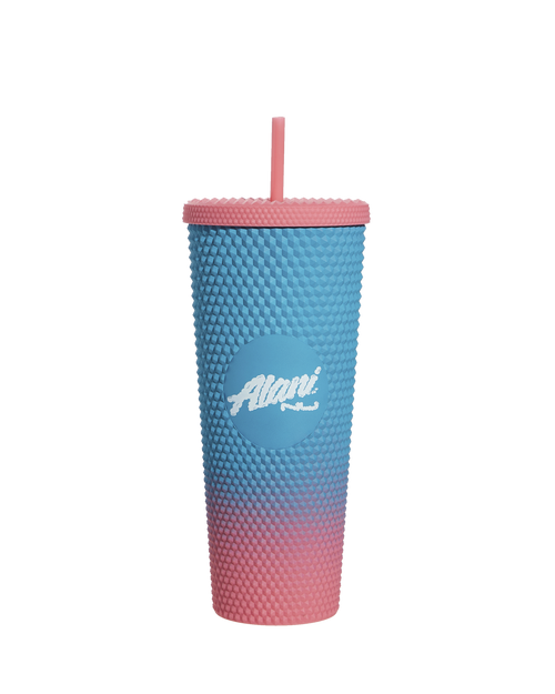 The Fly High Tumbler by Alani Nu is a textured, BPA-free cup with a lid and straw, featuring an ombre blue to pink gradient, complete with a central logo.