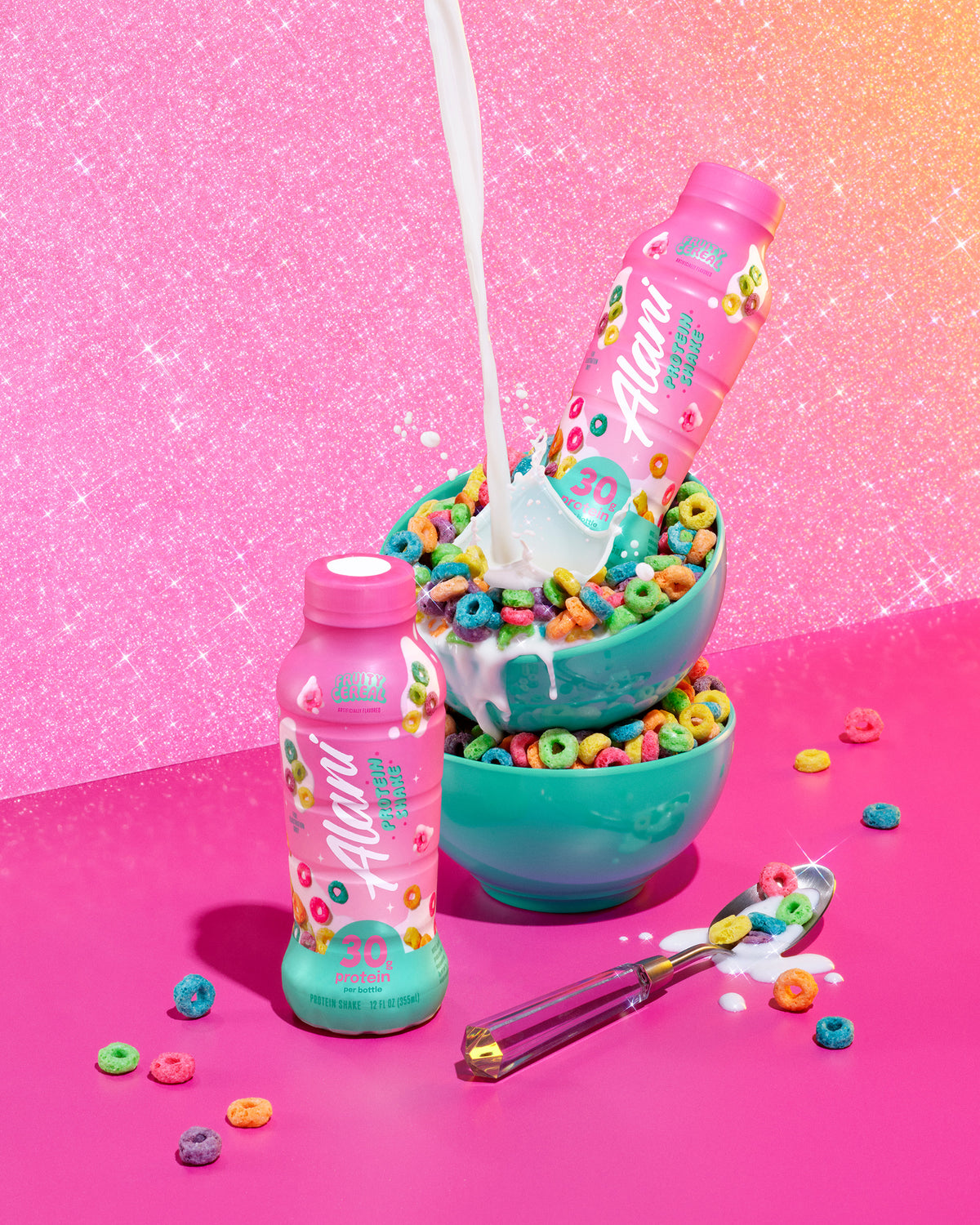 A whimsical image of two bottles of Fruity Cereal protein surrounded by classic fruity cereal, splashes of creamy milk and a sparkling pink background.