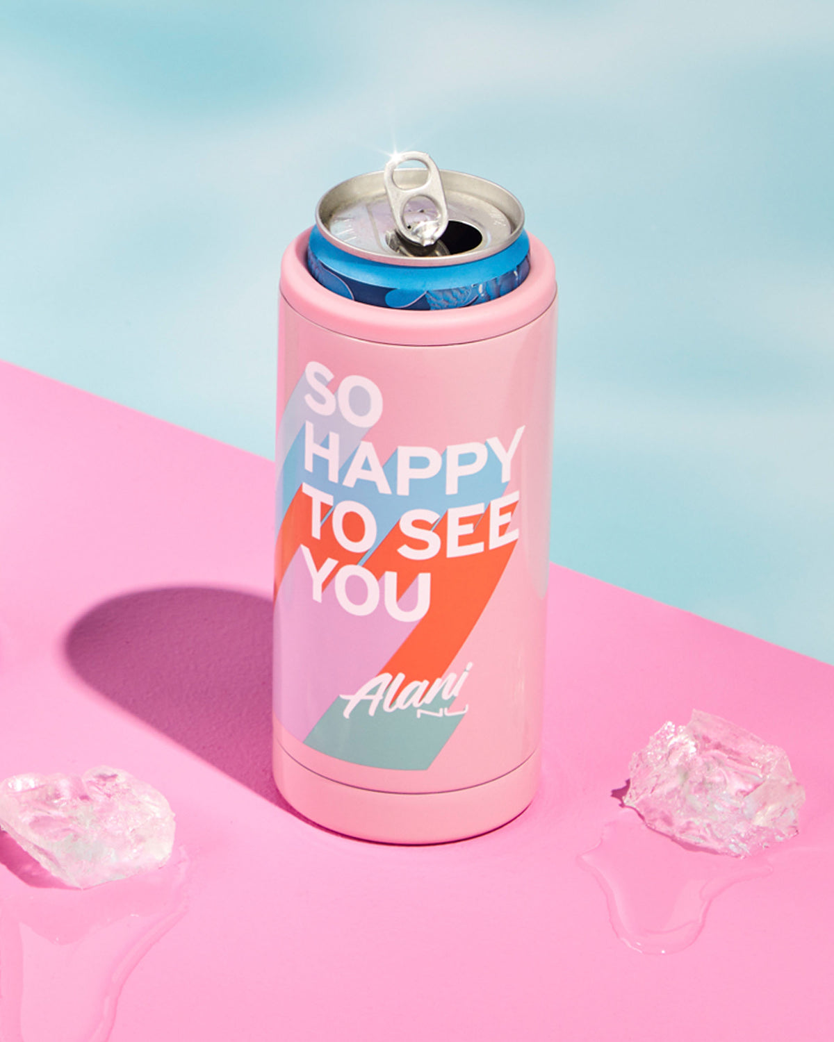 A Polar Pink Slim Can Chiller by Alani Nu, featuring &quot;So Happy To See You&quot; text, is chilled among ice cubes on a pink and blue background.