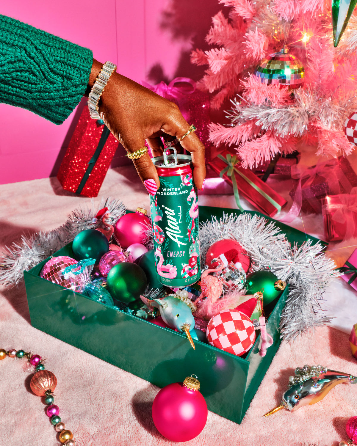 A bejeweled and manicured hand reaches into frame to pluck a can of Winter Wonderland from a box of ornaments. 